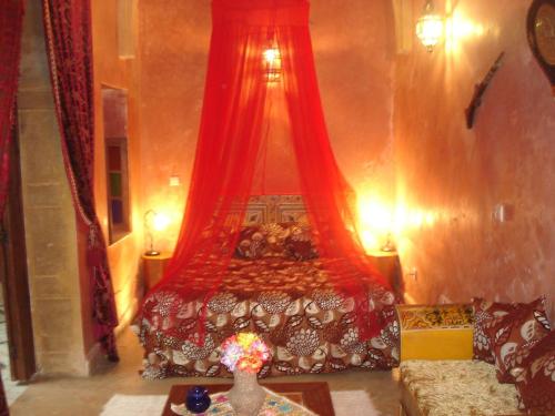 a bedroom with a large bed with red curtains at Riad Marlinea in Sale