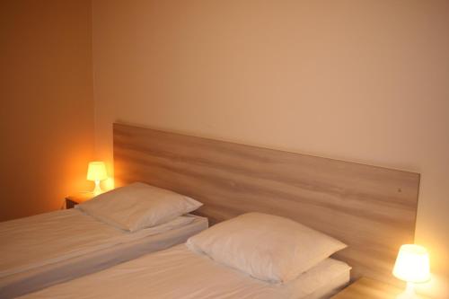 two beds in a bedroom with two lamps on them at Amicus Żoliborz in Warsaw