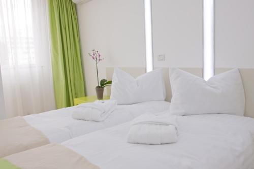 a white bed with white pillows and a green curtain at Christina Hotel in Bucharest