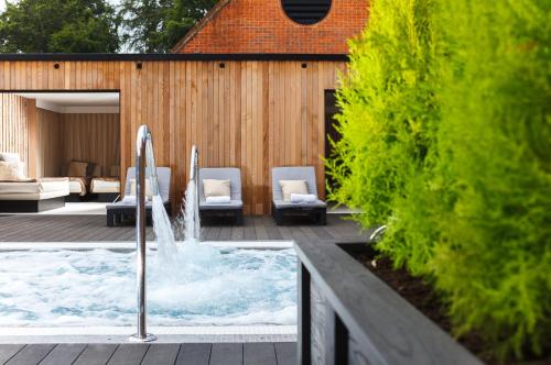 a swimming pool with two chairs and a fountain at Champneys Forest Mere in Liphook