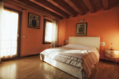 een slaapkamer met oranje muren en een wit bed bij Alloggi Alba in Vicenza