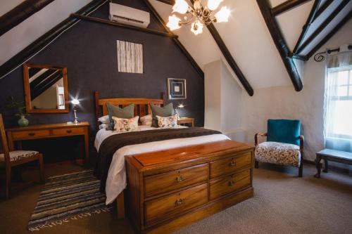 a bedroom with a large bed and a blue chair at Cypress Cottage Guest House in Swellendam
