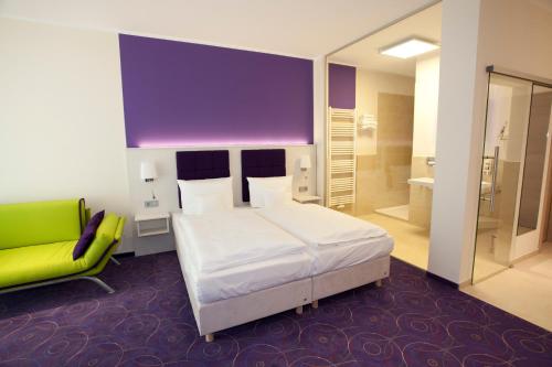 a bedroom with a white bed and a green chair at Hotel Waldperle in Graal-Müritz