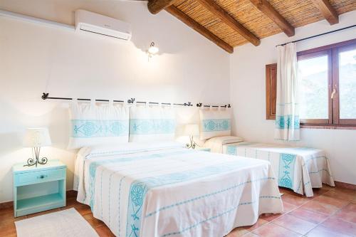 a white bedroom with two beds and a window at Hotel Sa Tanca E Bore in Siniscola