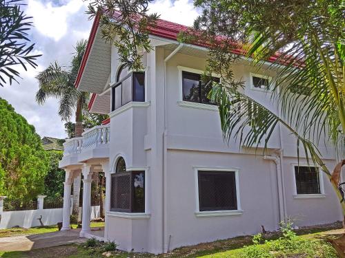 a white house with trees in front of it at Sofias House Rental in Tagbilaran City