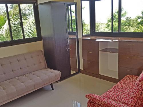 a room with a couch and a chair and windows at Sofias House Rental in Tagbilaran City