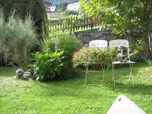 two chairs in a yard with flowers and a fence at Haus Alpenglühn in Sautens