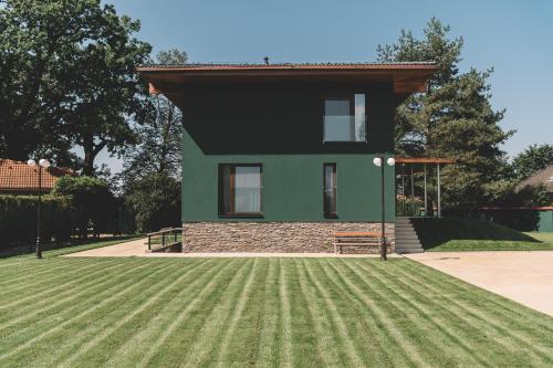 a green house with a grassy yard in front of it at Apartmány v rodinném domě in Hluboká nad Vltavou