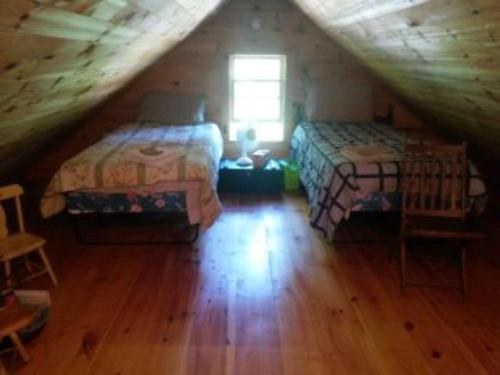 a attic room with two beds and a window at Camp Mitigwa Rental in Rangeley
