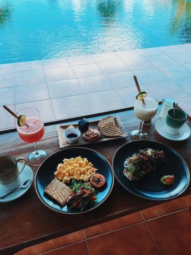 een tafel met borden eten en drinken naast een zwembad bij B Saya Villas in Ubud