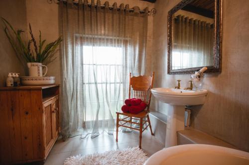 La salle de bains est pourvue d'un lavabo, d'un miroir et d'une fenêtre. dans l'établissement Cypress Cottage Guest House, à Swellendam