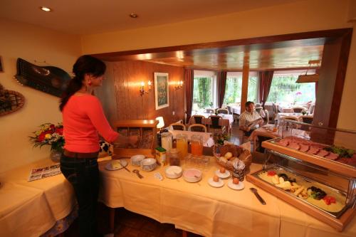 a woman standing in front of a buffet in a restaurant at Hotel Bellevue in Riezlern