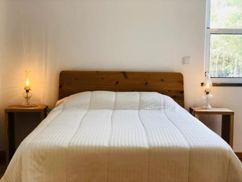 a bedroom with a bed with two lamps on two tables at Casa d'Avó Francisco in Madalena