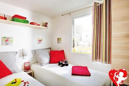 een slaapkamer met 2 bedden en rode kussens bij Les Hauts de Lastours in Belvès