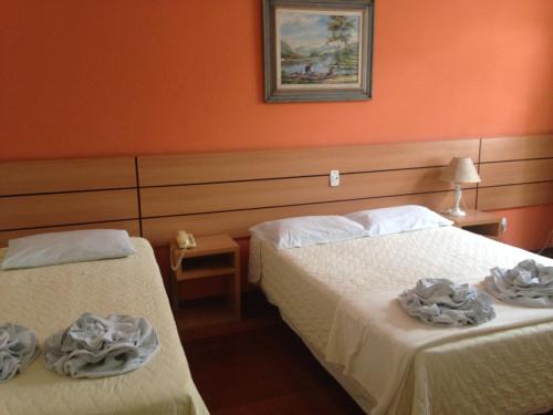 Duas camas num quarto com paredes cor de laranja em Hotel Colonial Aquarius em João Monlevade