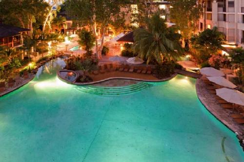 an empty swimming pool at night with a resort at Sea Temple Palm Cove 2 Bedroom Luxury Apartment in Palm Cove