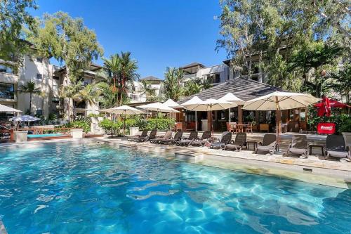 a swimming pool with chairs and umbrellas at Sea Temple Palm Cove 2 Bedroom Luxury Apartment in Palm Cove