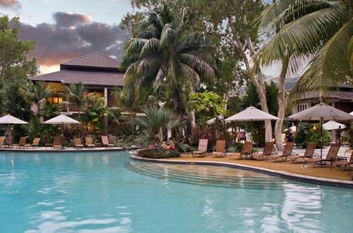 a pool at a resort with chairs and umbrellas at Sea Temple Palm Cove 2 Bedroom Luxury Apartment in Palm Cove
