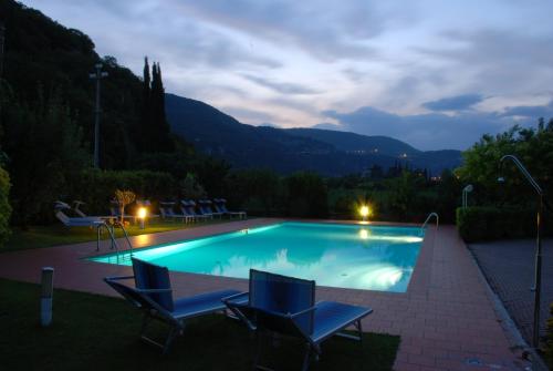 a swimming pool at night with two chairs and a playground at Hotel La Pergola in Grezzana