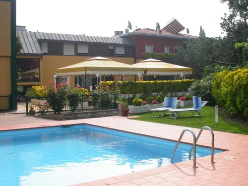 a swimming pool in a yard with chairs and umbrellas at Hotel La Pergola in Grezzana