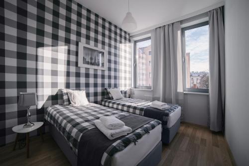 two beds in a room with checkered walls at Apartamenty 1 Maja 45 in Elblag