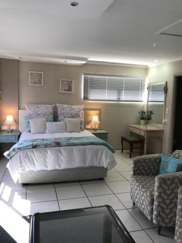 a bedroom with a bed, chair, and table at Bay Breeze Guesthouse in Gordonʼs Bay