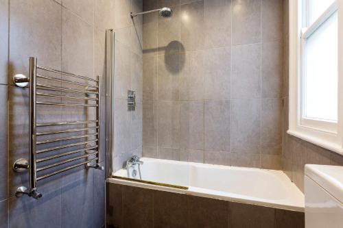 a bathroom with a white tub and a shower at Veeve - First Avenue Retreat in London