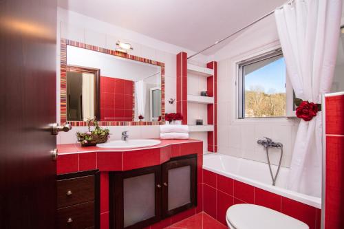 een rode badkamer met een wit bad en een wastafel bij Maisonette Stefanie in Limenas