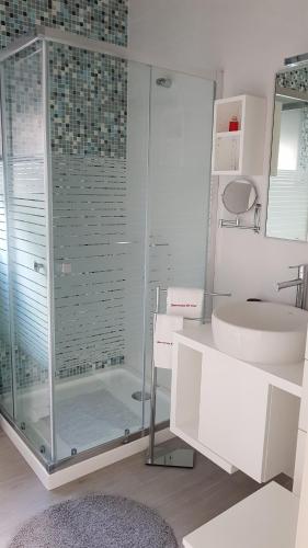 a bathroom with a glass shower and a sink at Barrocas do Mar in Prainha de Baixo