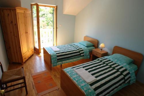 1 dormitorio con 2 camas, silla y ventana en Apartments Casiopea, en Postira