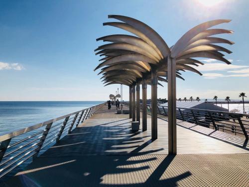 a pier with a palm tree on the beach at White Loft Alicante in Alicante