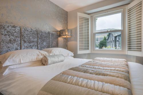 a bedroom with a large white bed with a window at Haven Cottage in Ambleside