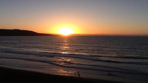 a sunset on the beach with the sun setting at Numancia 1 - 2A in Las Palmas de Gran Canaria