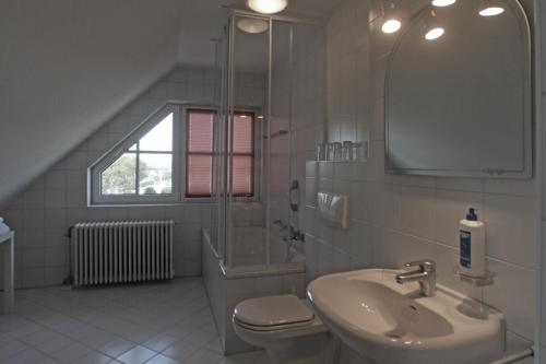ein Badezimmer mit einem Waschbecken, einem WC und einem Spiegel in der Unterkunft KIRCHERS PARK-HOTEL KAISERSTUHL Garni in Endingen