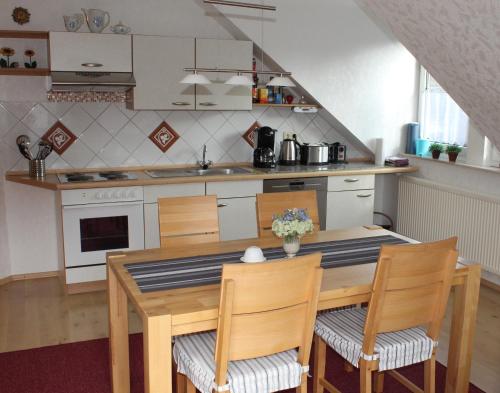 une cuisine avec une table en bois, des chaises et un comptoir dans l'établissement Ferienwohnung Kredig, à Poppenhausen