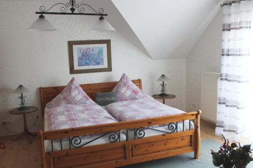 1 dormitorio con cama de madera y almohadas rosas en Ferienwohnung Kredig en Poppenhausen
