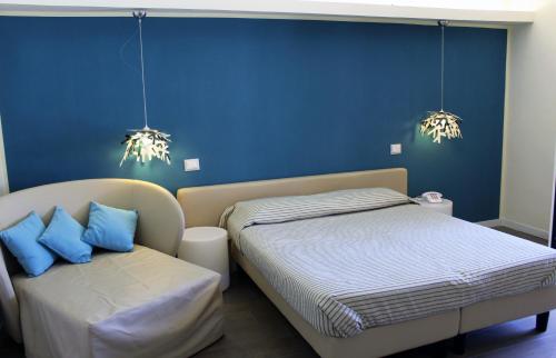 1 dormitorio con 1 cama y 1 silla con paredes azules en Hotel Mare, en Agropoli