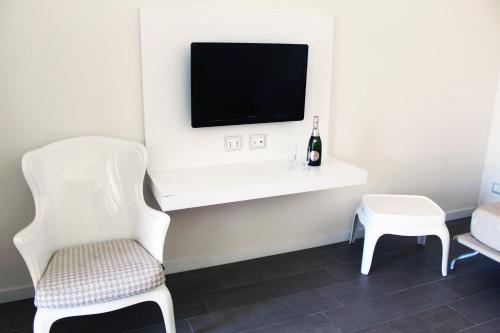 Habitación con silla blanca y TV. en Hotel Mare, en Agropoli