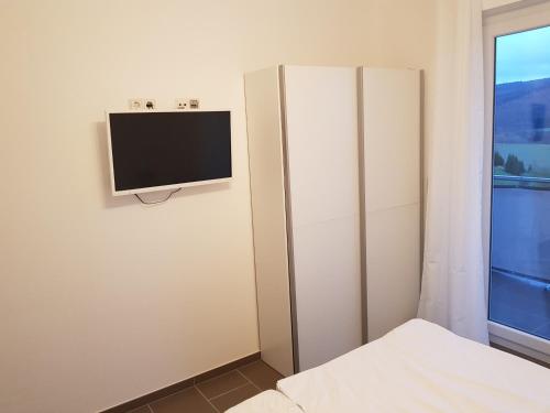 a bedroom with a flat screen tv on the wall at FeWo Lena in Kinderbeuern