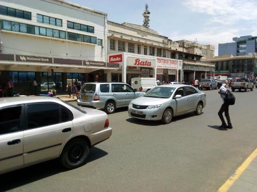 a man standing in the middle of a busy street with cars at Mona Lisa Guest House, Kisumu in Kisumu