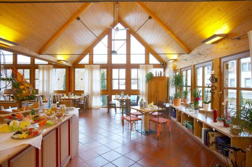 Habitación grande con mesas, sillas y ventanas. en Dohlmühle Gästehaus & Weingut, en Flonheim