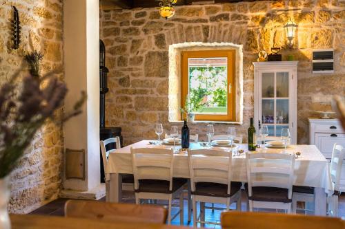 un comedor con una mesa con sillas blancas y una ventana en Rural house Mudrinic "Ivini dvori" en Bogatić