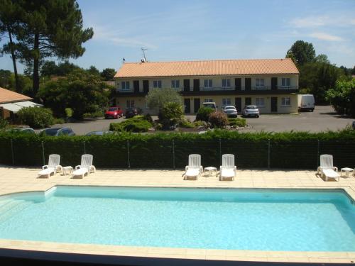 a swimming pool with lounge chairs and a building at Hôtel Restaurant Les Bruyères in Saint-Médard-en-Jalles