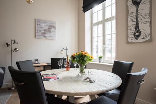 een eettafel met stoelen en een vaas met bloemen bij Cozy & Bright Apartment in Antwerpen