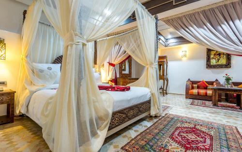 - une chambre avec un lit à baldaquin et des rideaux dans l'établissement Hotel & Ryad Art Place Marrakech, à Marrakech