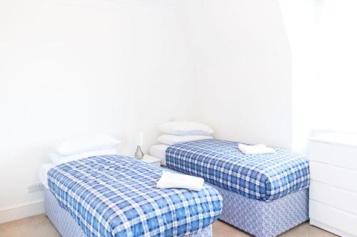two twin beds in a room with white walls at Access Little Venice in London