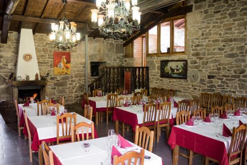 a dining room with tables and chairs and a fireplace at Casa Roan y Casa Grande in Lodoso