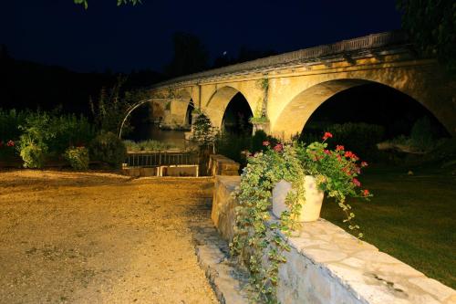 a stone bridge with flowers in a park at night at Hôtel Restaurant Plaisance-Piscine couverte et chauffée- Proche Sarlat- in Vitrac