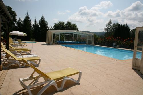 a swimming pool with lounge chairs and a building at Hôtel Restaurant Plaisance-Piscine couverte et chauffée- Proche Sarlat- in Vitrac