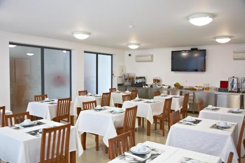 a restaurant with white tables and chairs and a kitchen at Solar de Alqueva in Reguengos de Monsaraz